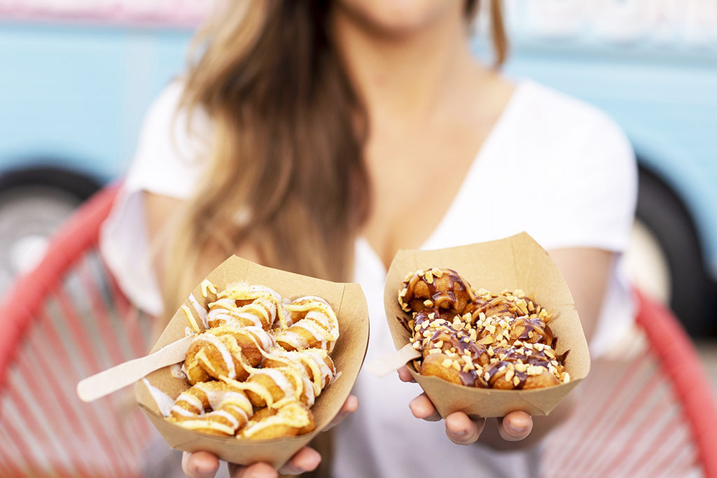Customer-blurred-holding-key-lime-pie-and-coconut-joy-donuts